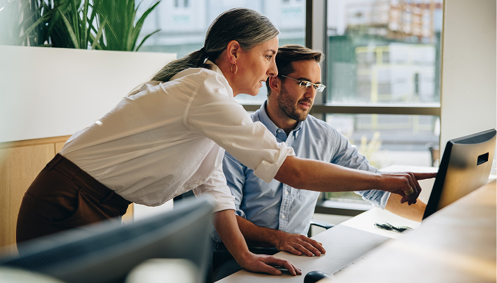 Man and woman looking and pointing at a screen in an office environment