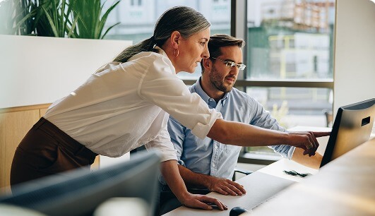 Man and woman pointing at computer screen in office